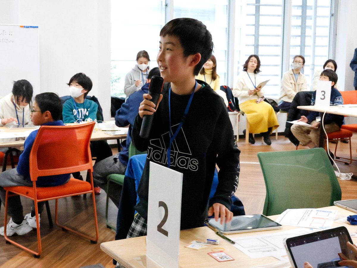 マイクを持って自分の作品を発表する子ども