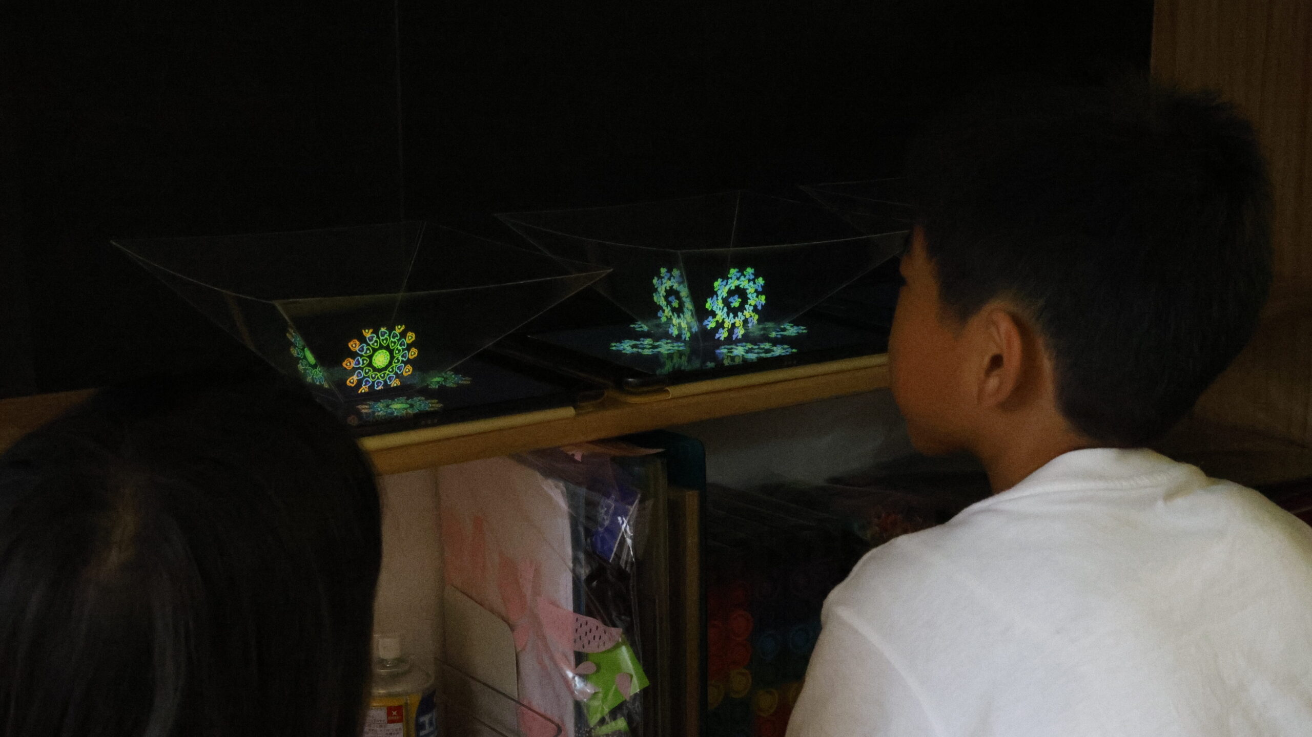 小学生がホログラム装置を使って、浮かび上がる動く花火を観察している様子