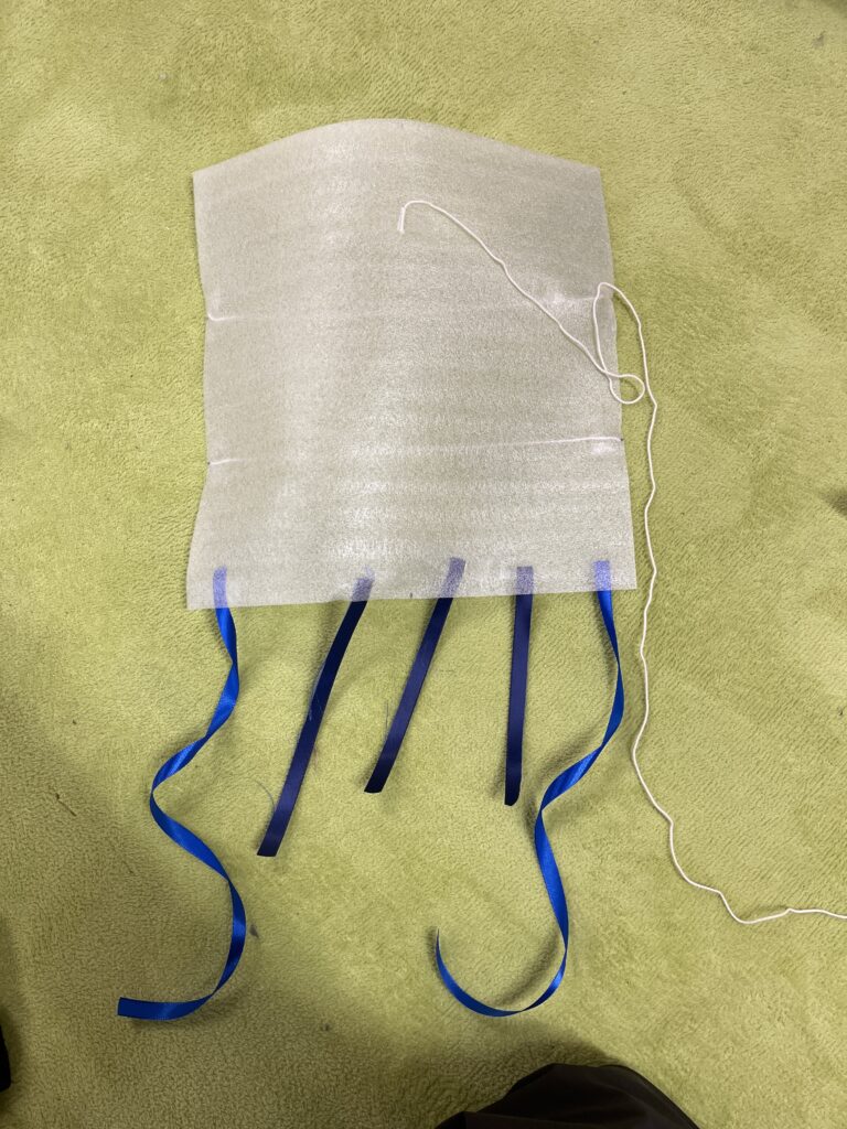 長さを測って取り付けた、青いリボンの『しっぽ』が特徴的な手作りの凧（たこ）