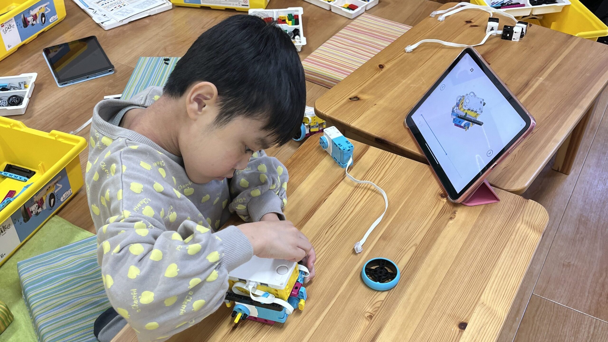 タブレットの組み立て図を見ながら、真剣な表情でレゴロボットを組み立てる男の子