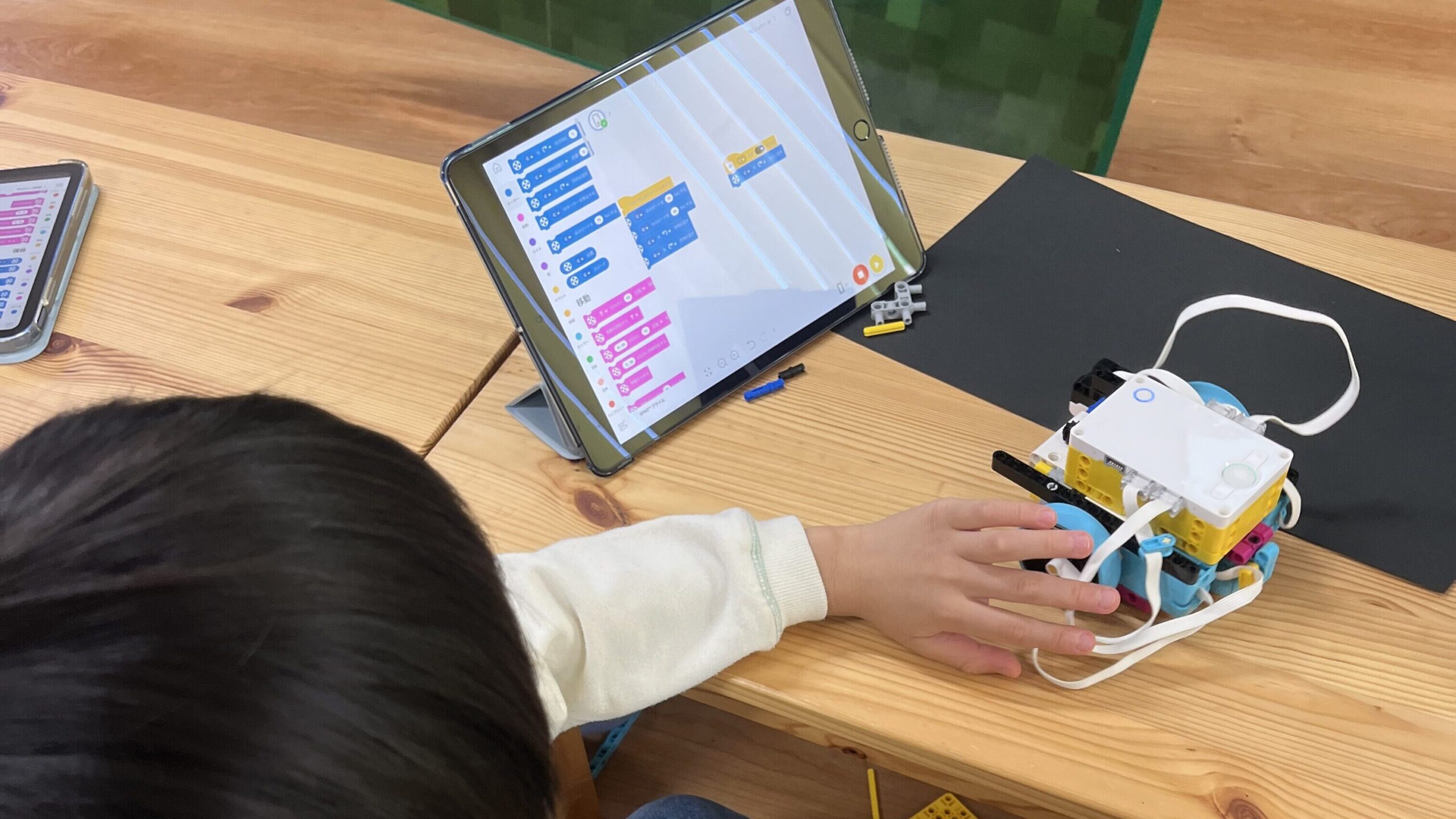 タブレットでプログラミングコードを作成し、手元のレゴロボットに転送して動作確認をしている様子