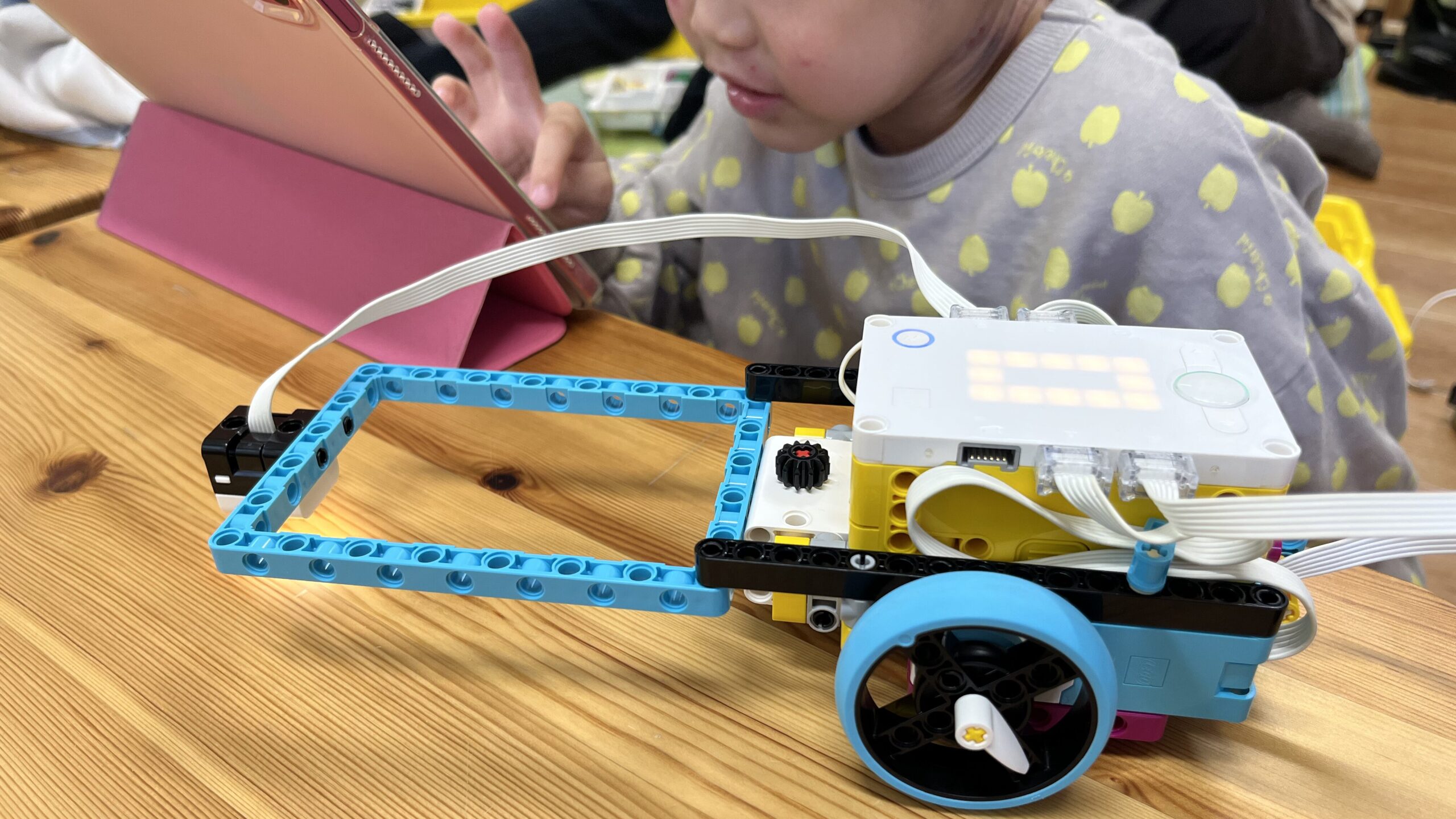 タブレット端末を使って自作のレゴロボットを制御し、動作確認とプログラムの修正を行っている様子