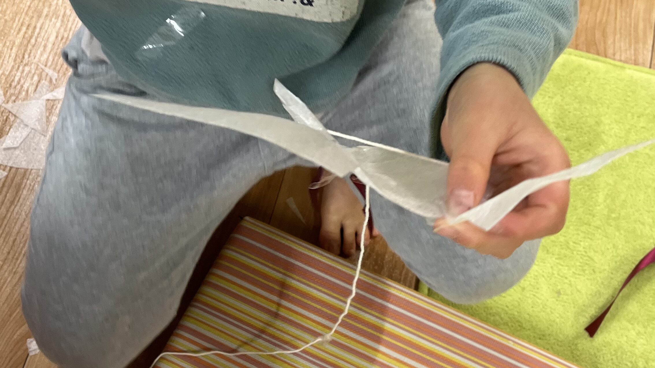 小学生の男の子がハサミを使い、凧をつくっている。