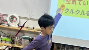 小学生の男の子が自作の凧をあげている。
