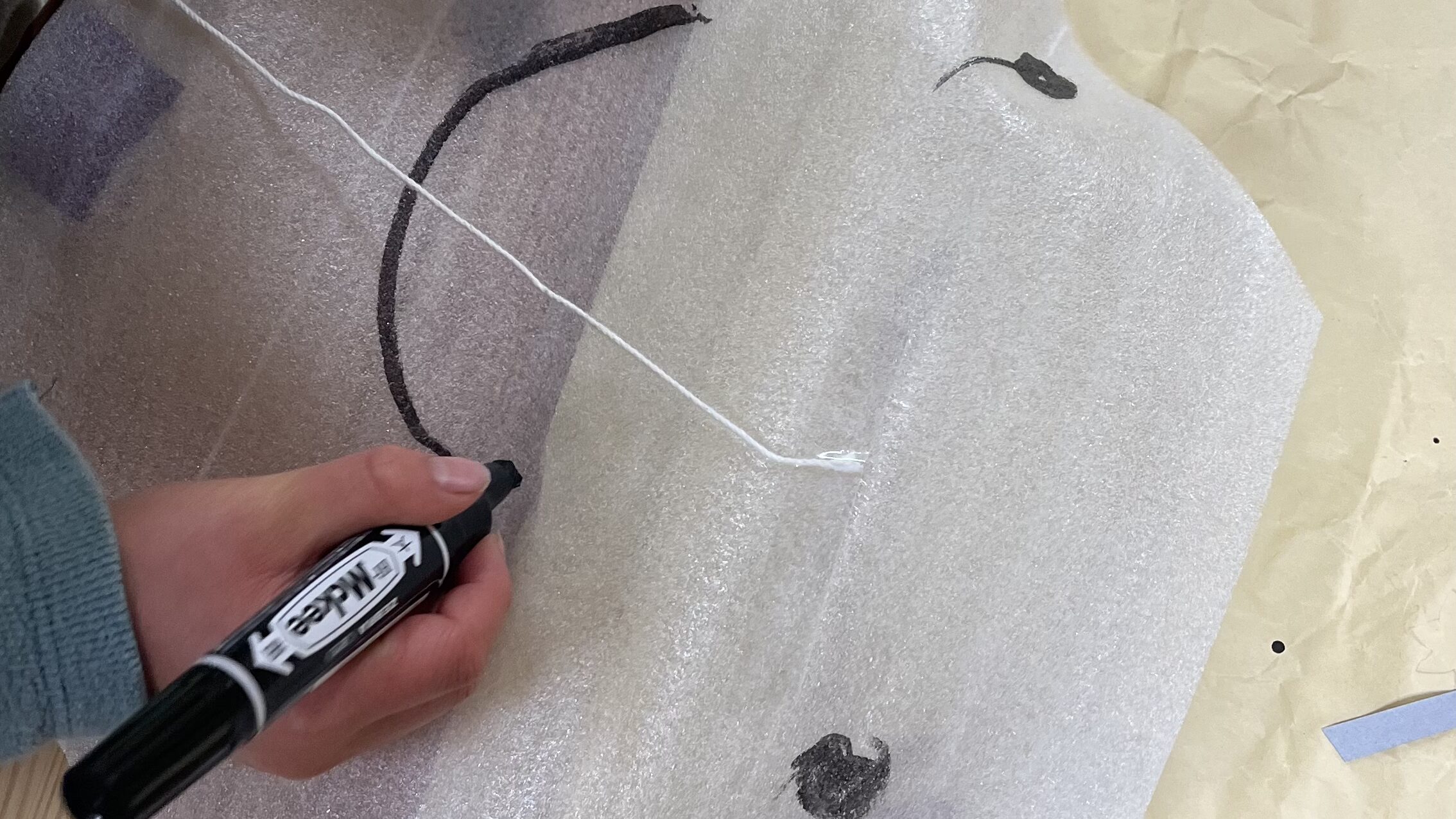 小学生の男の子が凧を自作し、顔を描き足している。