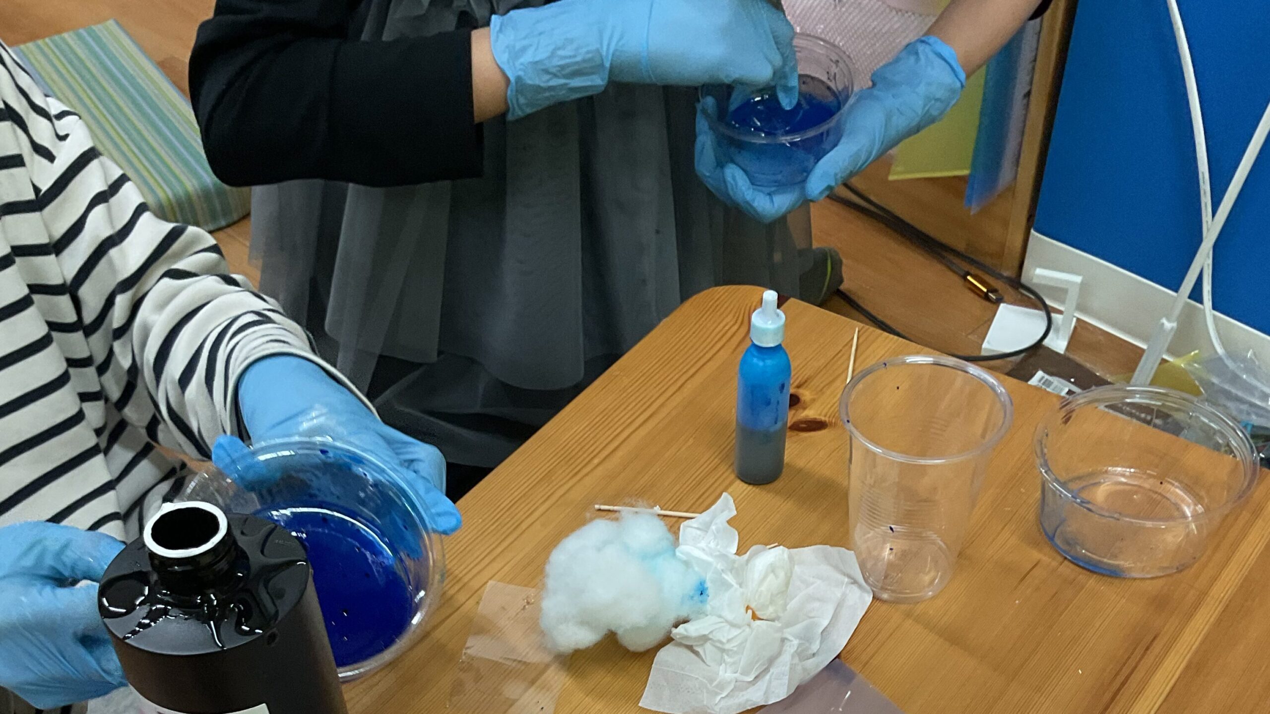 小学生二人が、プラスチック容器にレジン液と青いインクを入れて工作をしている。
