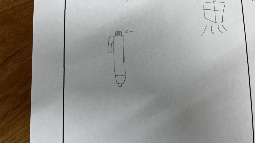 ノック式のペンを簡略化して描いた子供の手描きイラスト。上部のノック部分に矢印が引かれている。