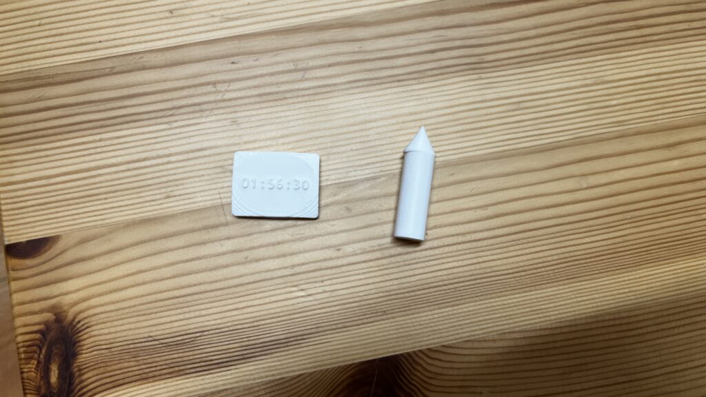 3Dプリンターで作られた、青色のプラスチック製のペンのような試作品。子供が描いた発明スケッチを立体化したもの。