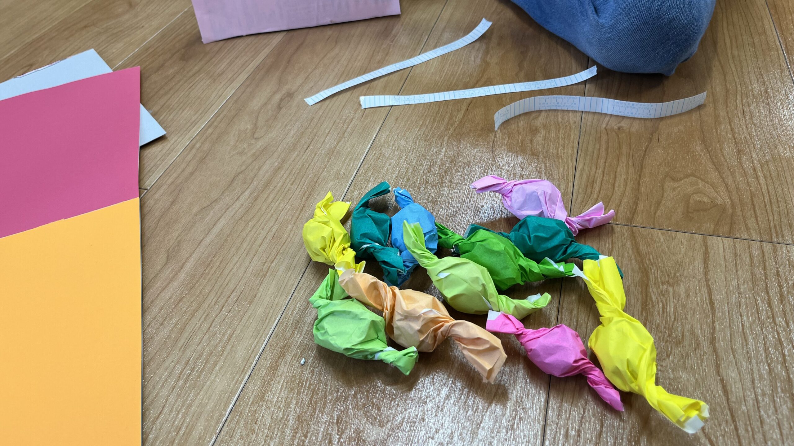 カラフルな包み紙キャンディ風の作品が床に並ぶ様子｜バレンタイン工作（小学生）