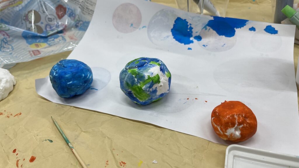 粘土で作った惑星に色を塗った作品例 青い星 地球っぽい星 オレンジの星が並ぶ