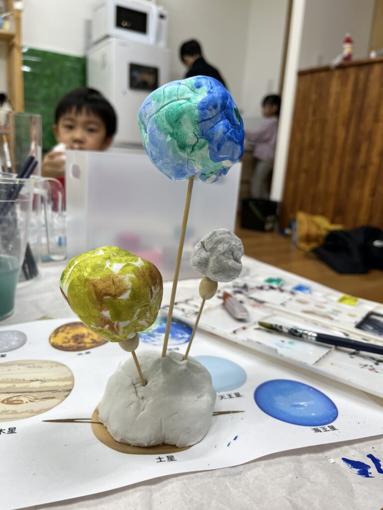 天地の日のSTEAM工作で作った地球と月の立体模型 竹串で高さをつけて宇宙空間を表現する様子（府中のSTEAM工作教室Pendemy）