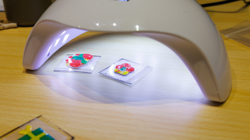 UVライトでレジンを硬化させている様子、ボンボンドロップ風シールをぷくぷくに仕上げる工程