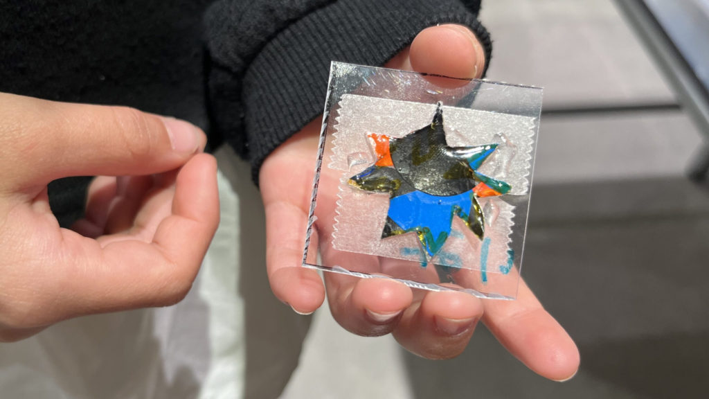 完成したボンボンドロップ風シールを手に持って見せている様子、黒と青を中心にした星形デザインのぷくぷくシール