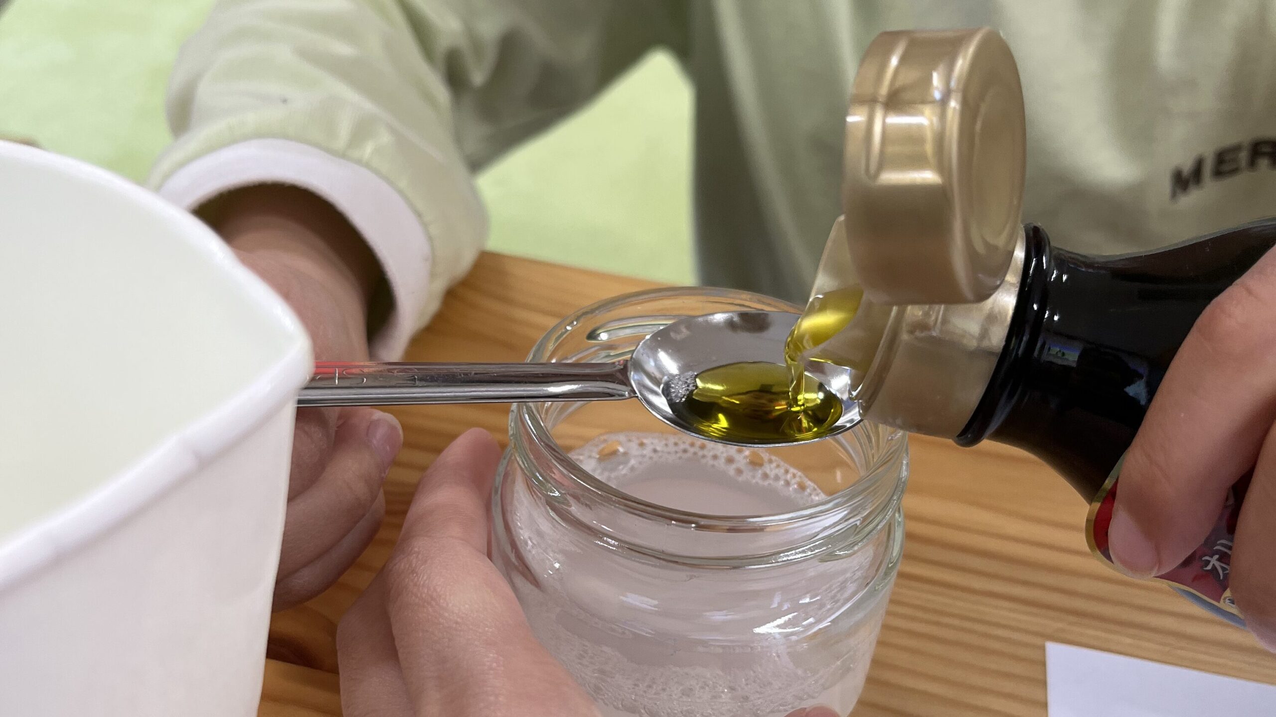 理科の実験に取り組む子供の様子。机の上には、クエン酸や塩、砂糖などのイラストが描かれたワークシート、白い粉末が入った袋、コップ、文房具が置かれています。