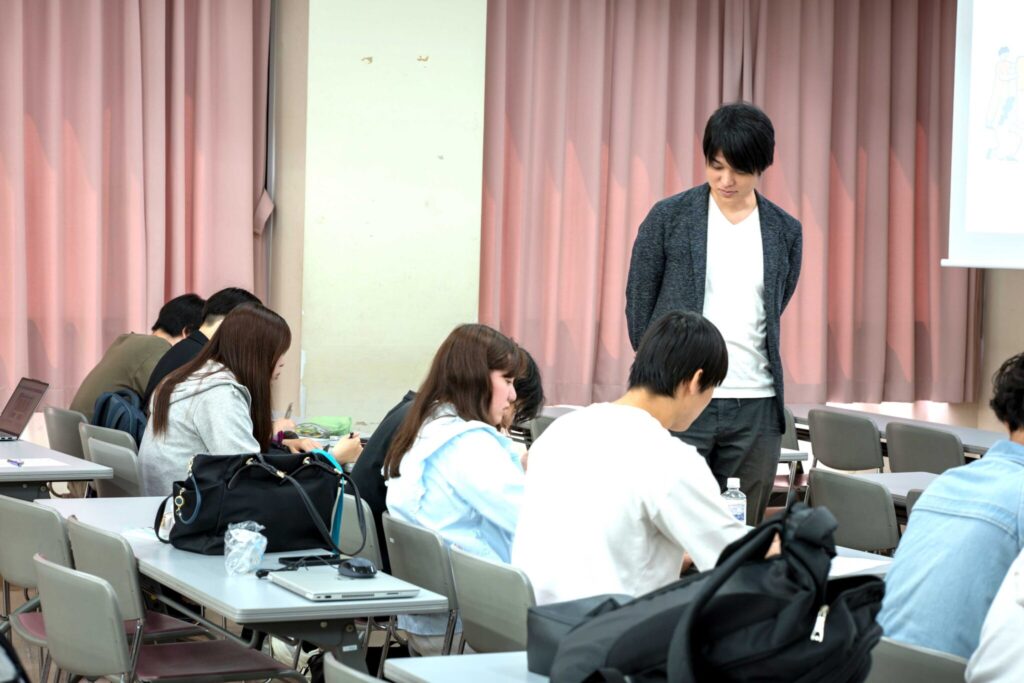 教育機関での講義で、着席した学生のあいだを回りサポートする講師