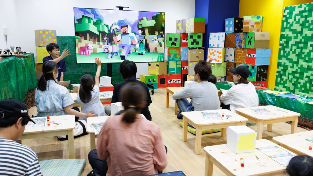 スクリーンに映るマインクラフトの映像を見ながら、元気に手を挙げる小学生