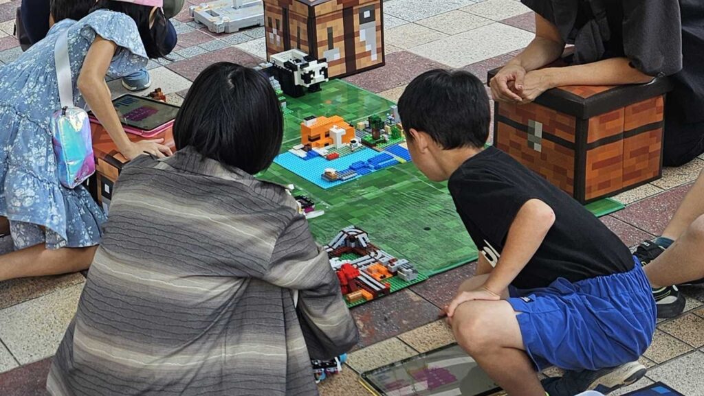 タブレットでプログラミングしたレゴのロボットを動かし、フィールド上のお宝集めに挑戦する小学生