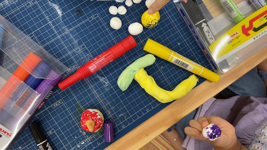 小学生が紙粘土とカラーペンを使い、バナナなどの食べ物を制作している秋の工作教室の様子