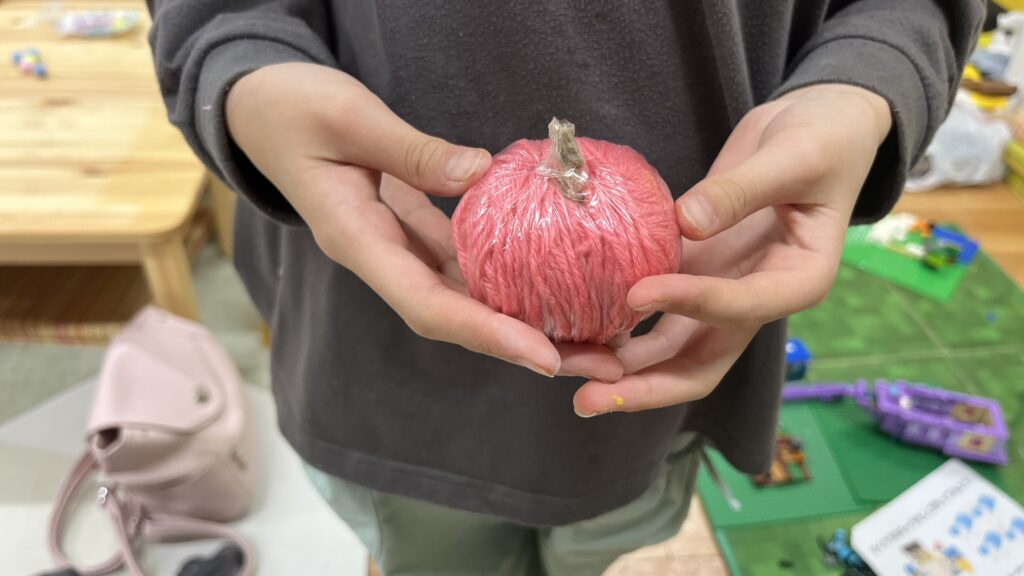 ピンク色の毛糸を巻いてりんごを立体的に表現した、小学生の秋の工作作品