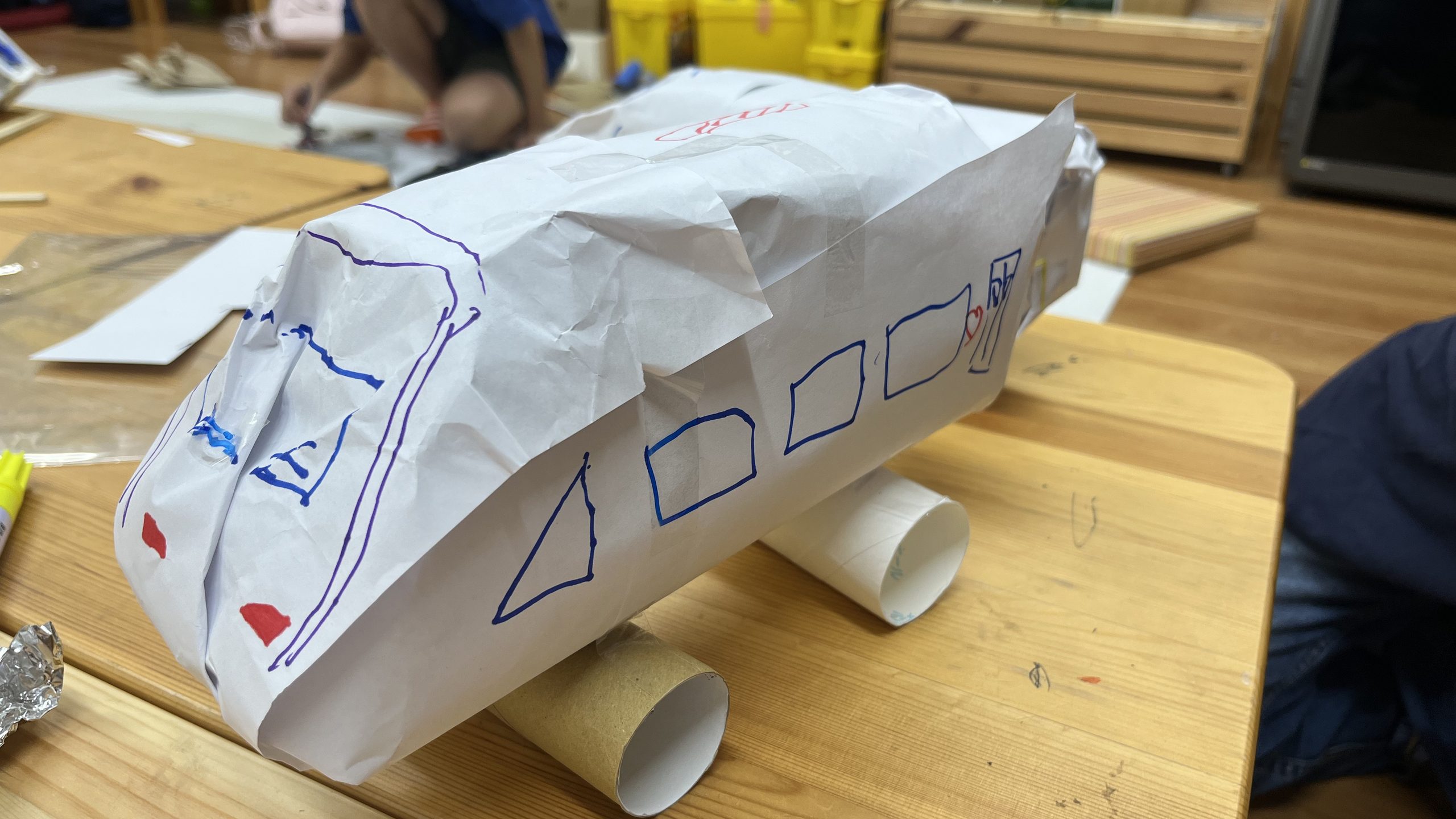 小学生向けSTEAM工作教室で制作した乗り物の工作作品。紙やトイレットペーパーの芯を使い、車輪や窓を工夫して表現
